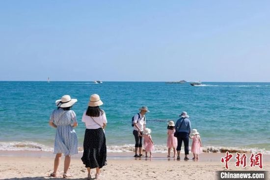 资料图:家长带着孩子在海边嬉浪。 游建行 摄