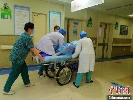 助产士刘琳琳在平车上以半跪的姿态托举住胎儿脐带。 董宇翔 摄