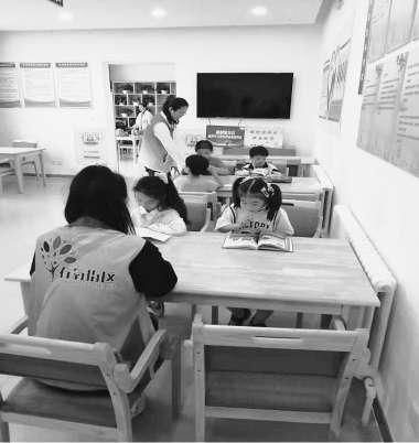 社区工作人员陪着孩子看书。
