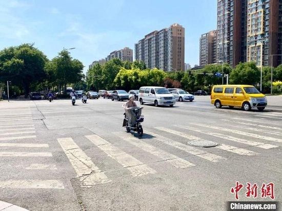 图为石家庄街头,顶着烈日出门的市民穿着防晒服,戴着遮阳帽。李晓伟 摄